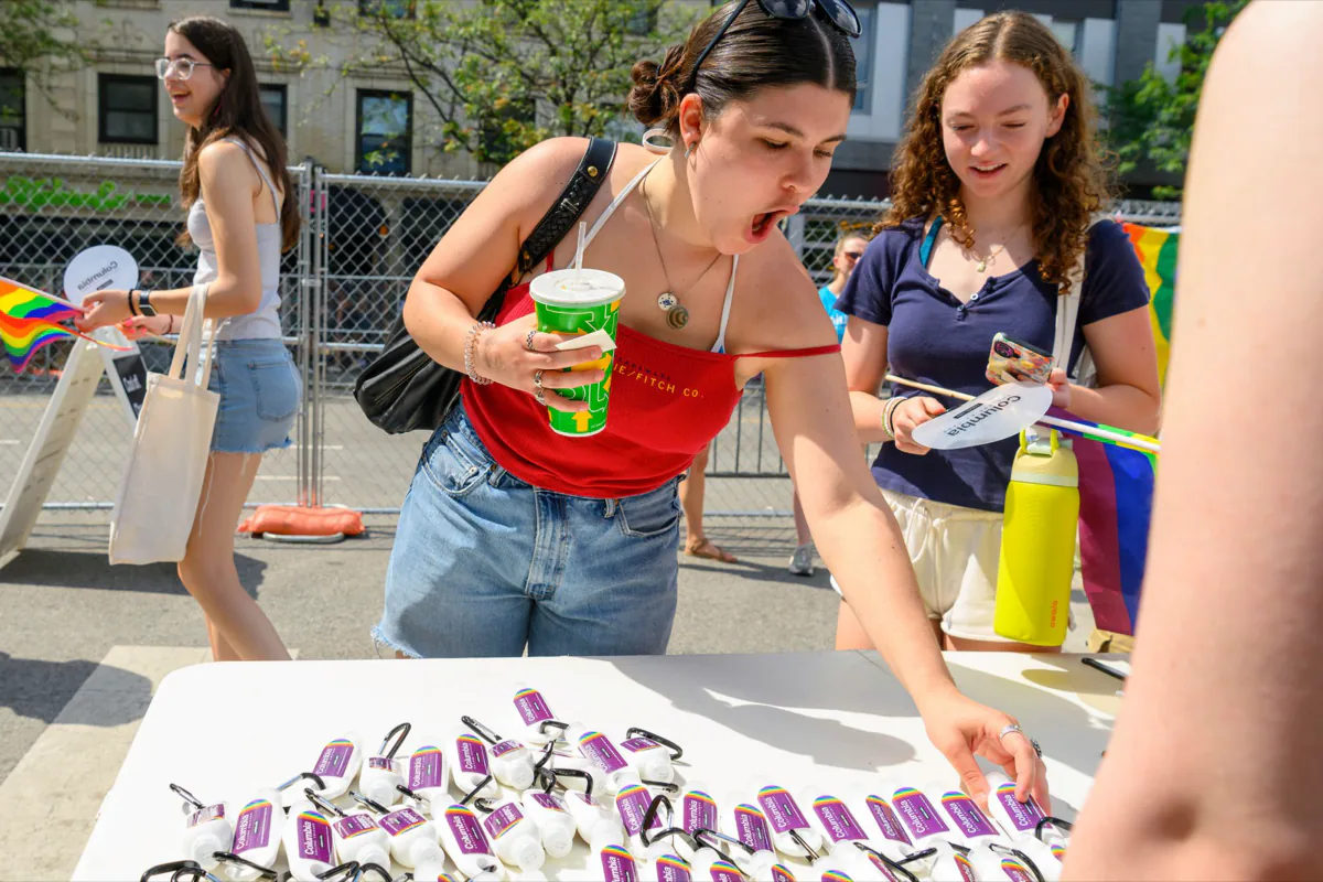 Paradegoer reacting with delight while reaching for Columbia-branded sunscreen at the giveaway table
