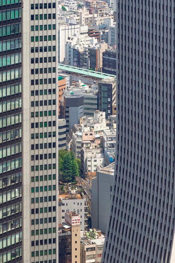 Tight composition of two skyscraper facades pressed together with only a narrow sliver of city visible between them