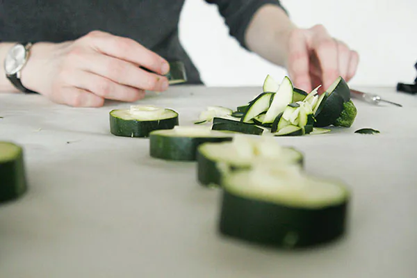 Process photo of hands slicing zucchini into rounds for the carved-letter poster